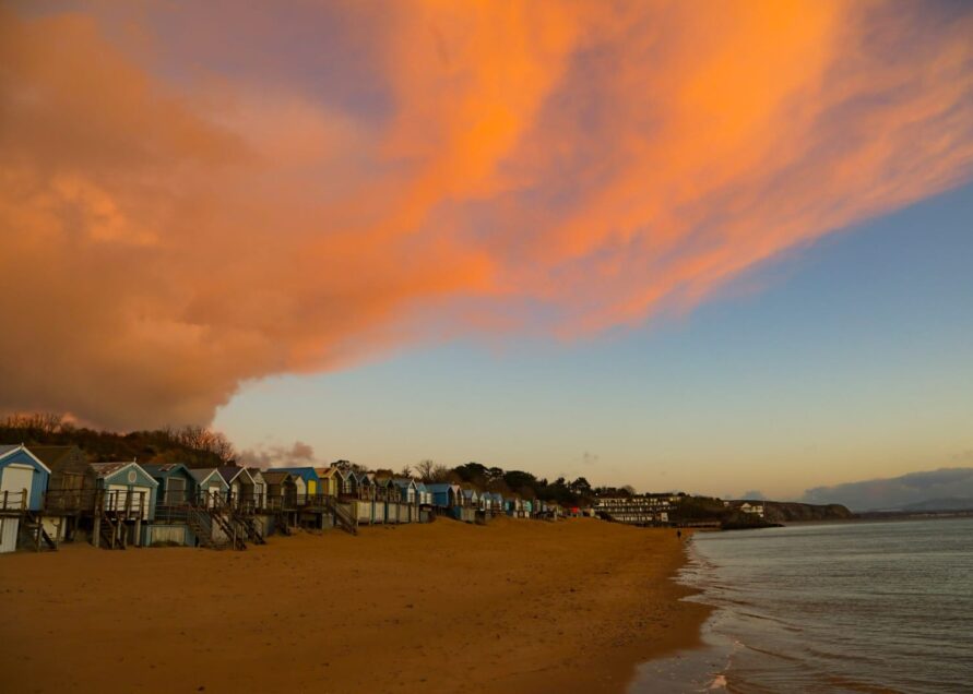 Snow clouds meet sunrise over the beach huts on Abersoch main beach
