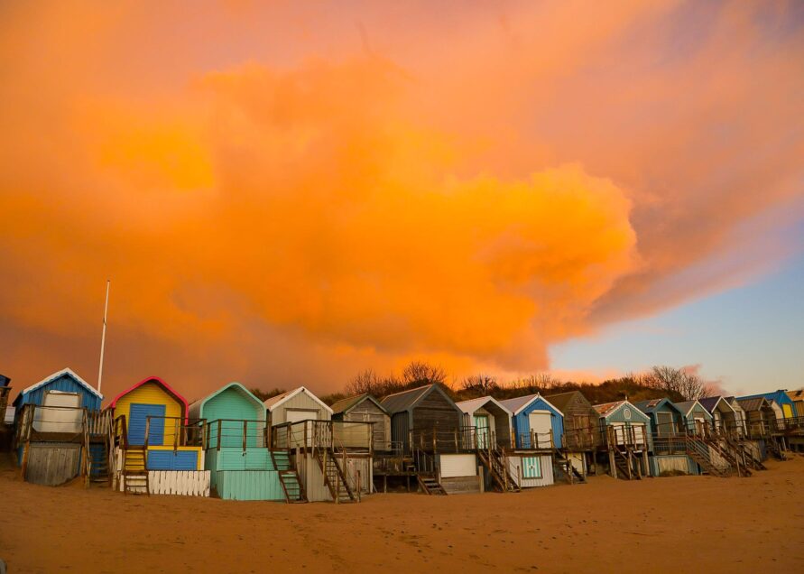 Snow clouds meet sunrise over the beach huts on Abersoch main beach